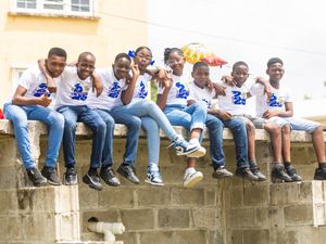 Seven students in Class of 2025 shirts sit together on a wall smiling for group photo.