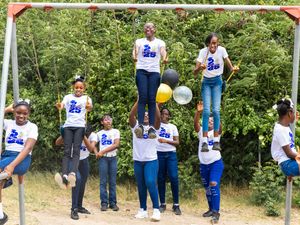 Students in Class of 2025 shirts pose playfully on playground equipment holding balloons.