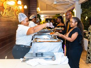 Catering staff serving food at a buffet event with chafing dishes at an elegant indoor venue.