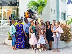 A joyful family group poses together outdoors near a decorative sculpture at a special celebration event.