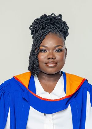 Young woman in blue and orange graduation gown smiling for a portrait photo.