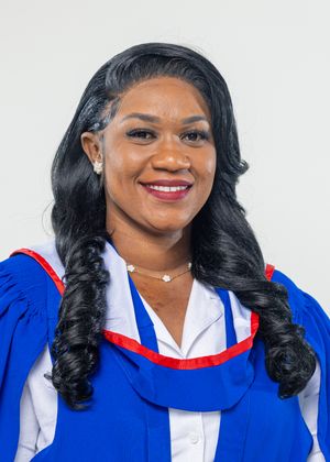 Smiling woman in blue and red graduation gown with long black hair at university ceremony.