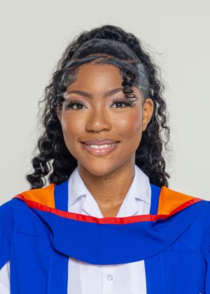 Young female graduate smiling in blue and orange academic gown with curly hair against neutral background.