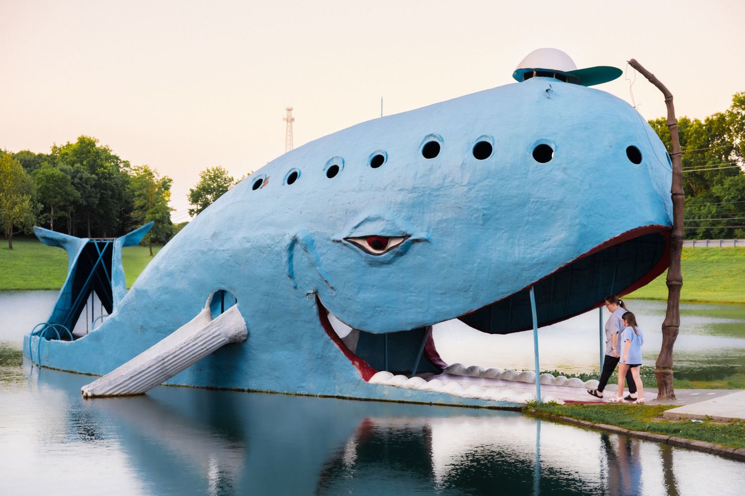 6. A woman and child walk into the mouth of the whale. Route 66 can be seen in the background. June 10, 2026.