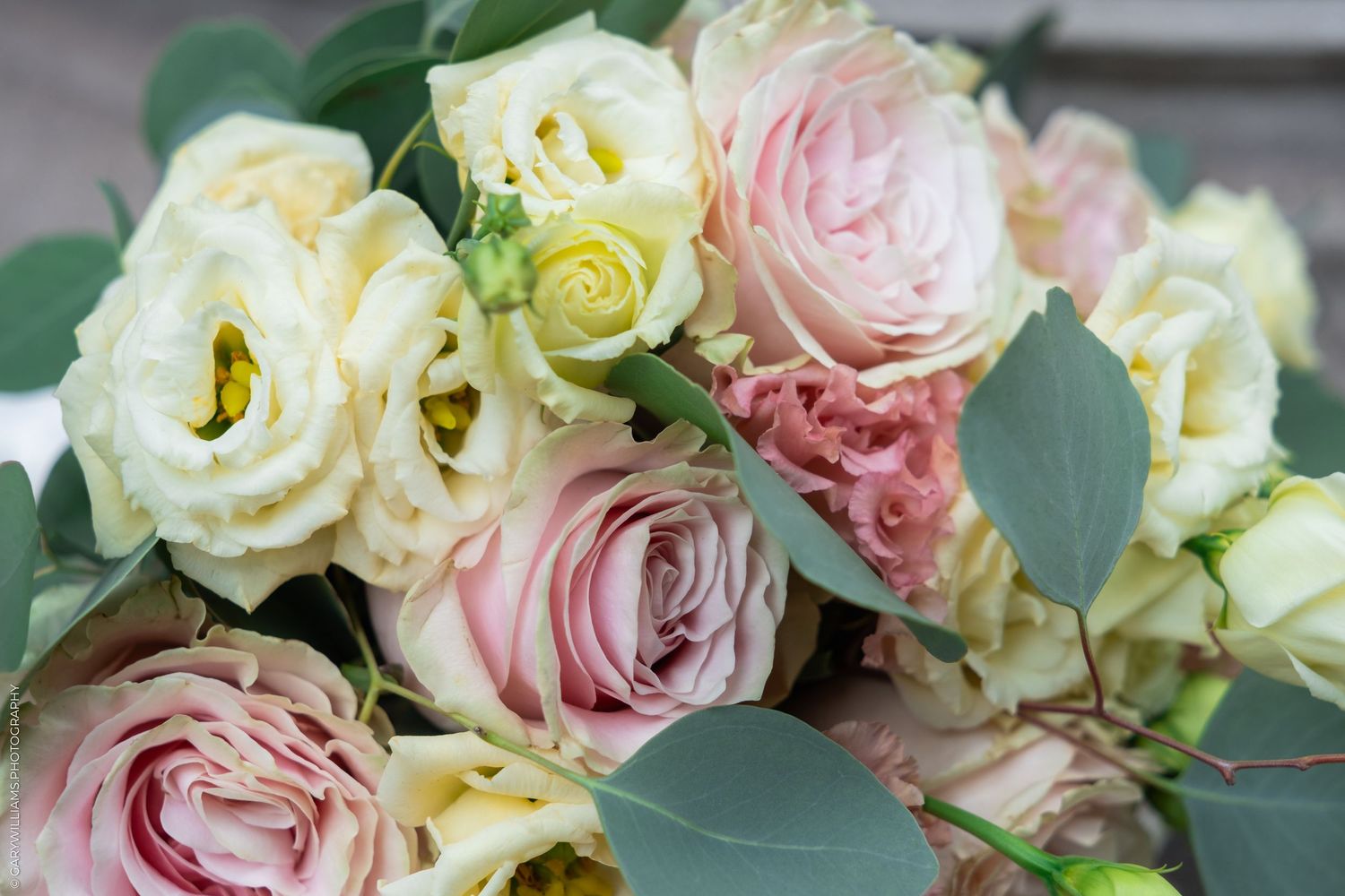 A romantic bouquet of pink and cream roses with eucalyptus leaves, perfect for weddings or special occasions.