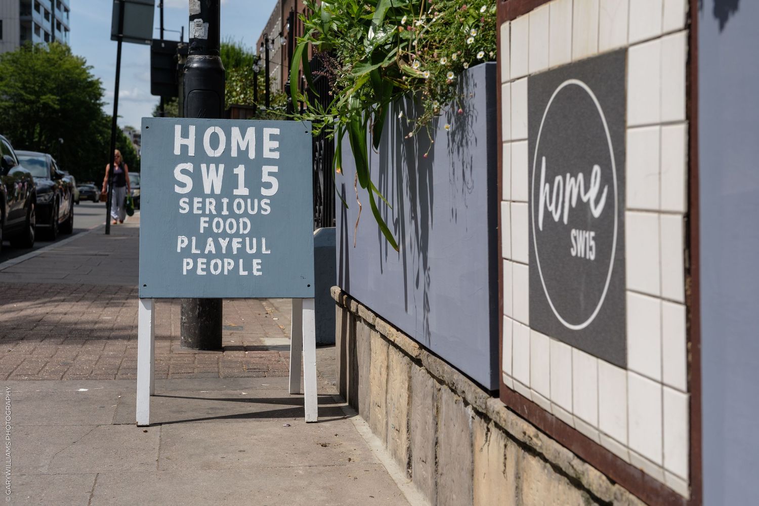 Home SW15 restaurant sign reading Serious Food Playful People on a sunny London street.