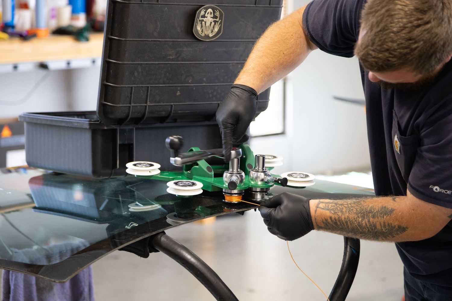 Technician in black gloves repairing auto glass using professional windshield repair tools and equipment.