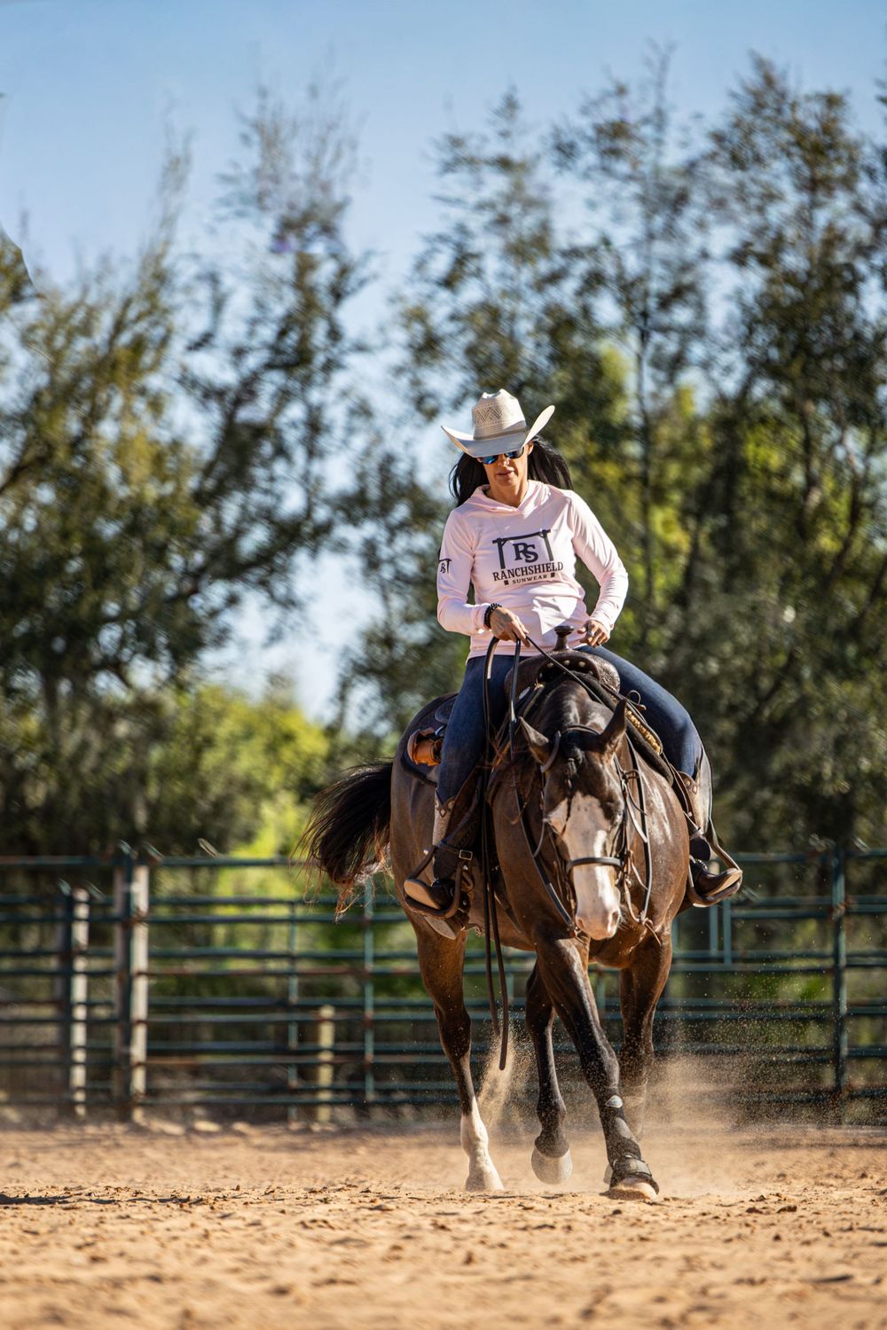 Female rider in white cowboy hat competing on horseback in sandy arena during western equestrian event.