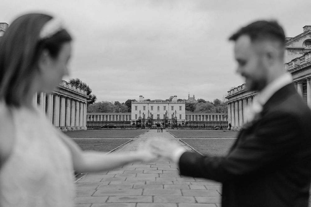 Black and white wedding photo of couple holding hands at Greenwich Naval College, London.