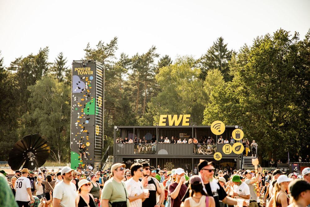 Large crowd gathered in front of the EWE Power Tower stage at an outdoor summer music festival.