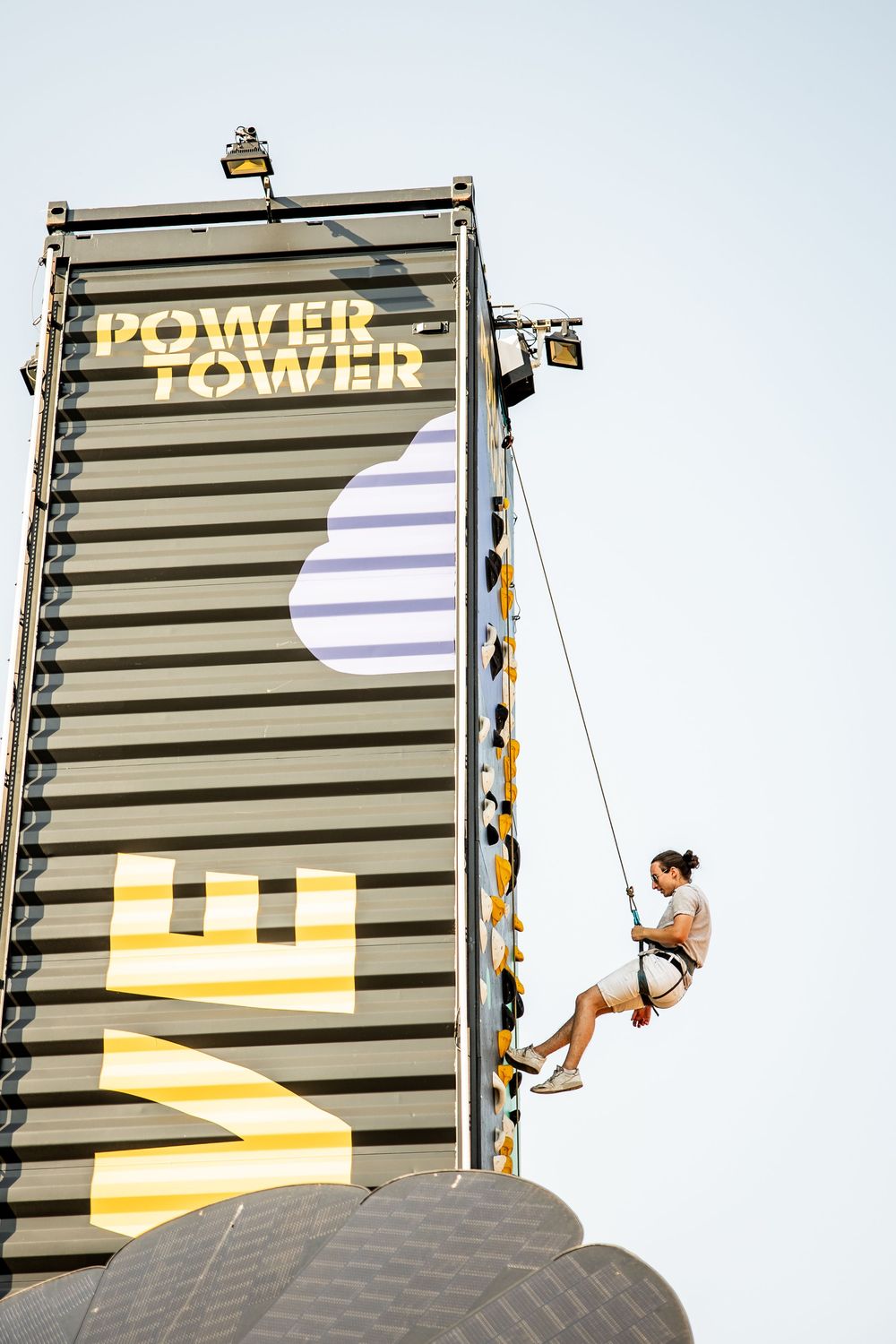 Person rappelling down the EWE Power Tower climbing wall at an outdoor music festival.