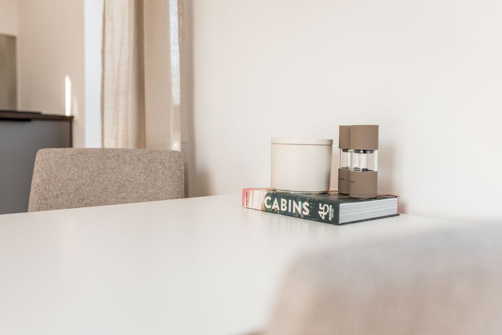 White dining table with Cabins book and decorative objects in a minimalist cabin interior.
