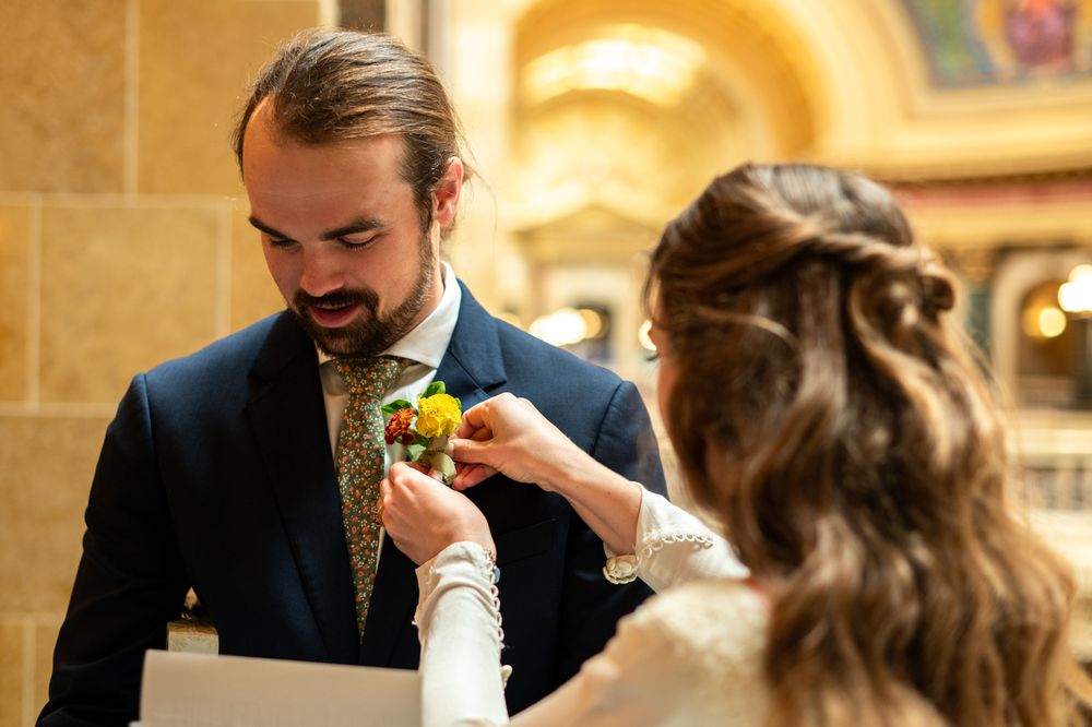 Bride adjusting groom's boutonniere in elegant venue.