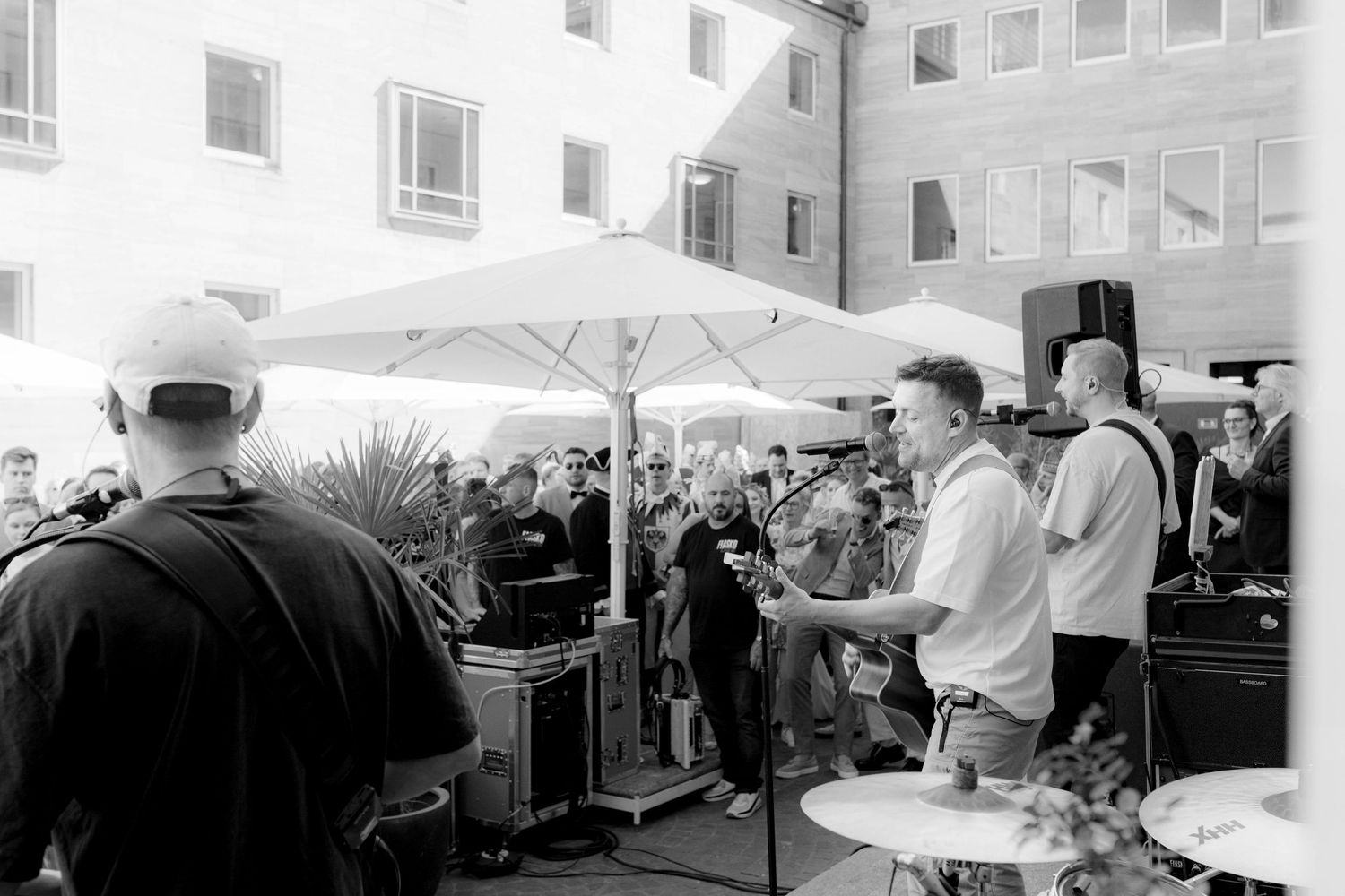 Black and white photo of a live band performing outdoors at a corporate event with an audience gathered around.