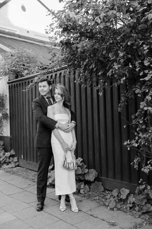 A sequence of black and white photos shows someone in a white dress peeking out from behind a fence with bushes.