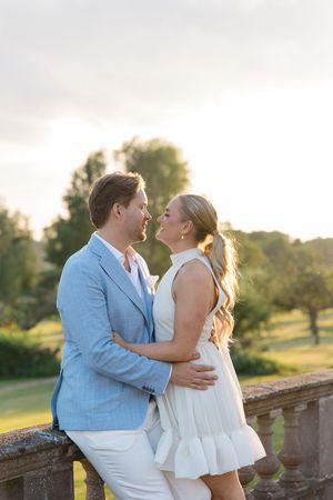 A couple shares an intimate moment during their engagement photoshoot at sunset in a garden setting.
