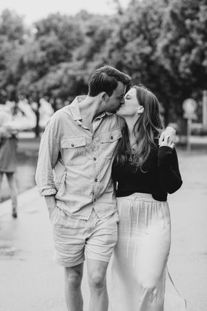 A romantic black and white photo of a couple embracing and sharing an intimate moment outdoors.