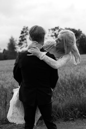 A couple dances together in a field during sunset, captured in a romantic black and white sequence.