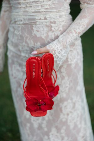 Red boxing gloves hang delicately against white lace wedding dress fabric creating a striking contrast.