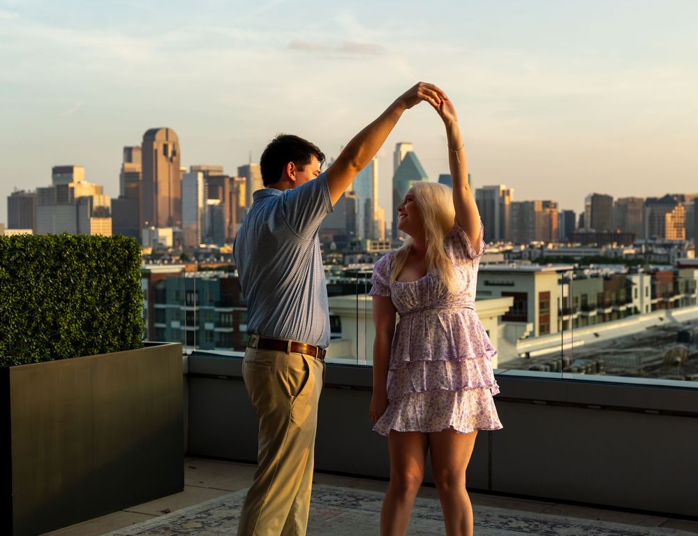 Couple dancing on a rooftop terrace with a stunning city skyline at golden hour.