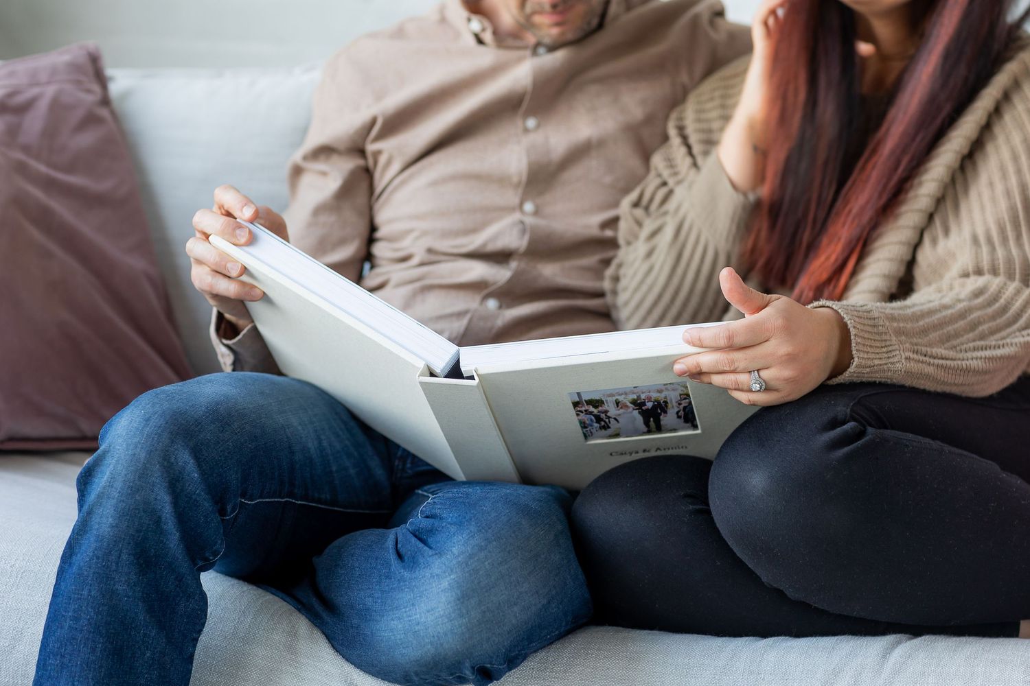 Two people reviewing a photo album together while sitting on couch.