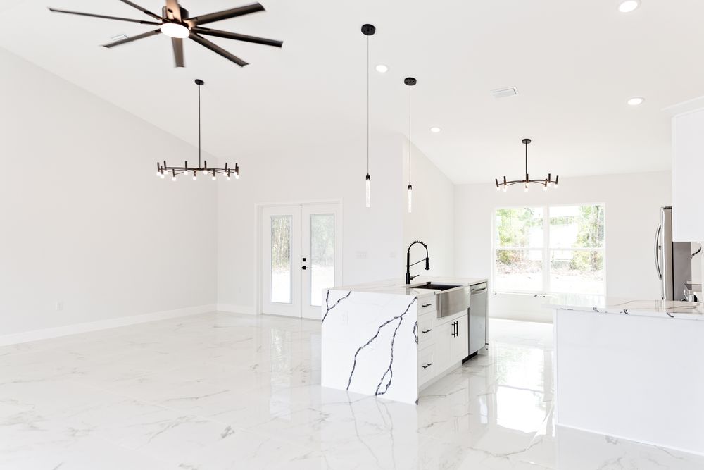 Bright open-concept kitchen with marble island, white floors, pendant lights, and ceiling fan in a modern home.