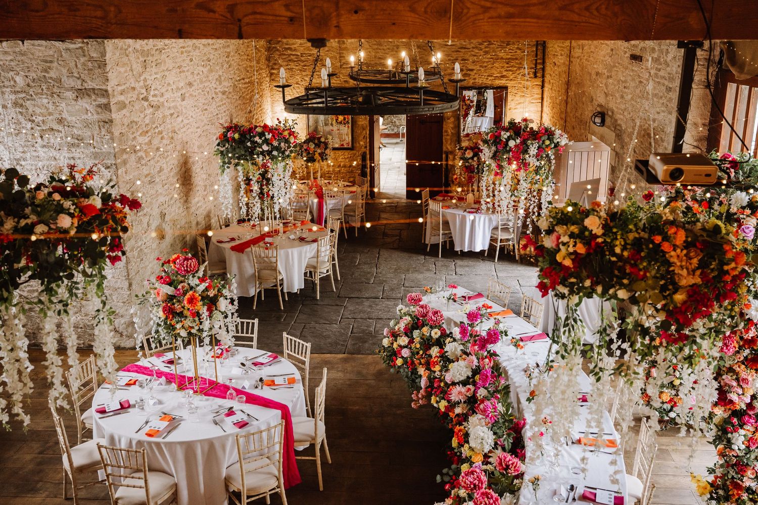 Elegant wedding reception in rustic barn with tall floral centerpieces featuring vibrant pink, red, and orange blooms Kingston Country Court