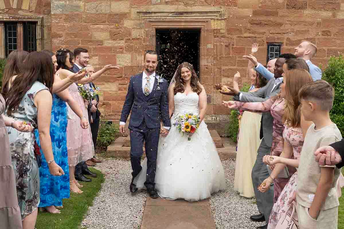 Couple walk through a sea of rose petals at Dalston Hall- Cumbria's premier wedding venue