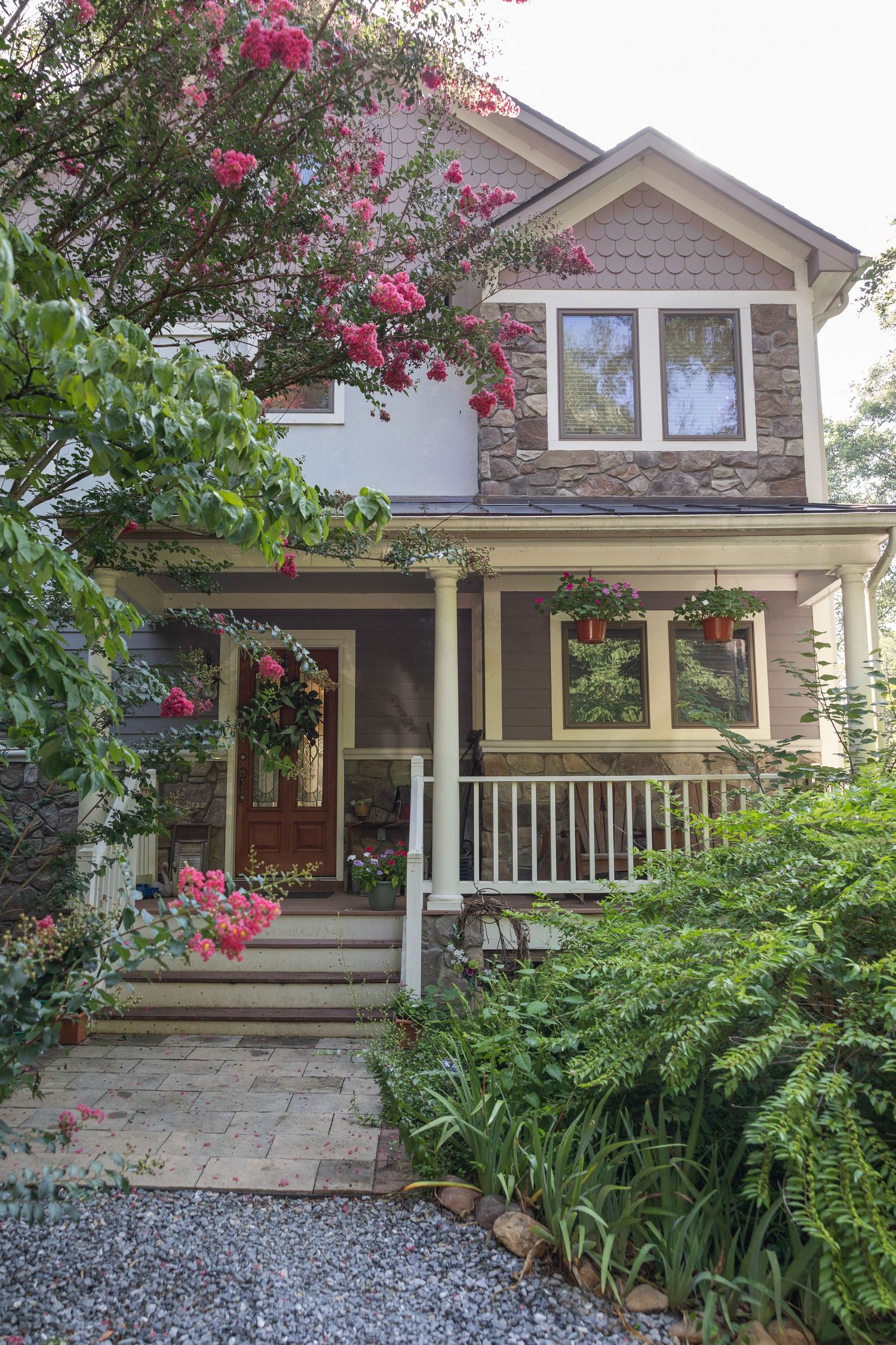 Charming Luray bed and breakfast with lush garden, pink flowering trees, white porch railing, and stone accents on a tree-lined path.
