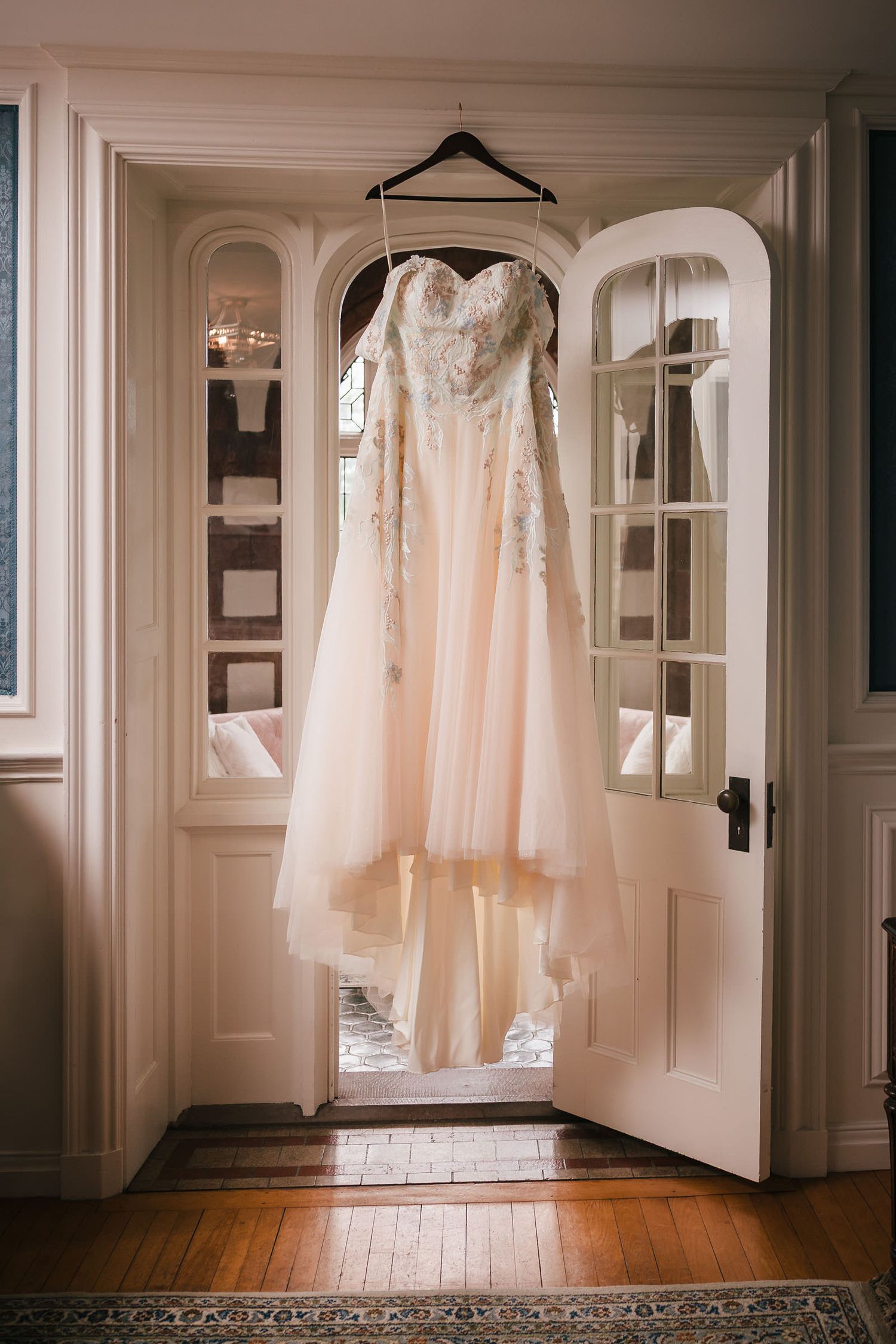 Bride's wedding dress with beaded floral embroidery hanging in an arched doorway at Searles Castle in Windham, New Hampshire