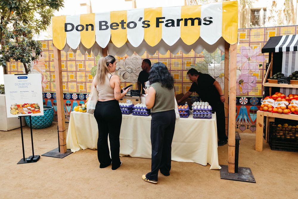 Customers browse fresh produce at Don Beto's Farms outdoor market stall with colorful display.