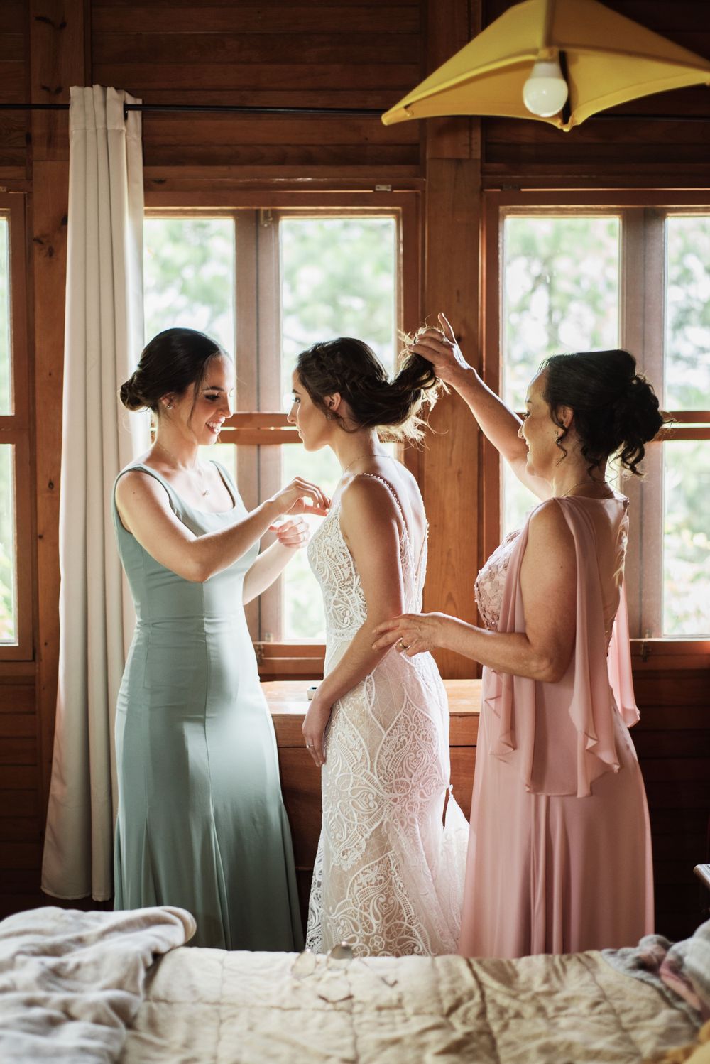 Novia, hermana y madre arreglando a la novia en el día de su boda