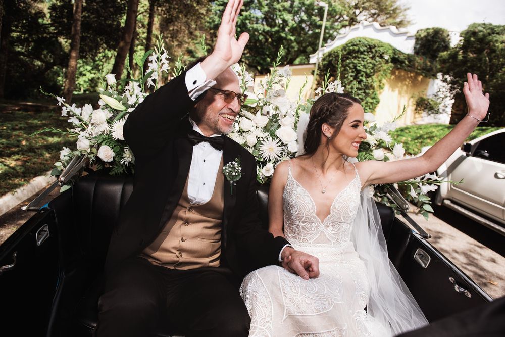 Padre de la novia y novia saludando desde el auto