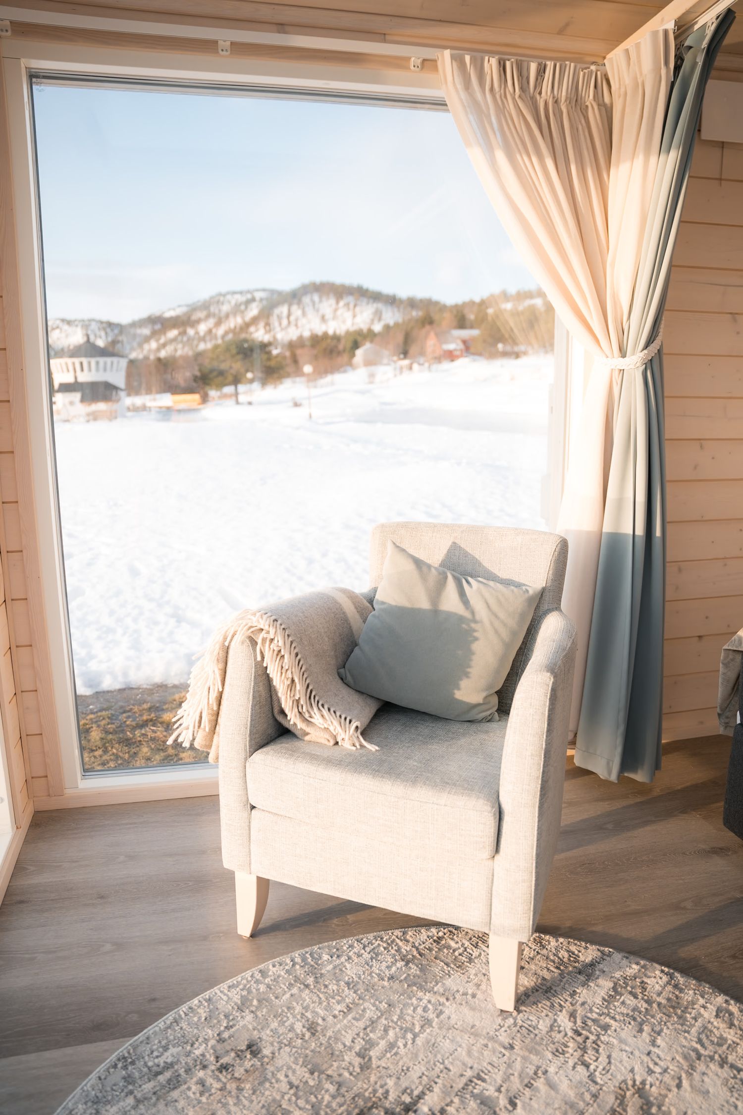 fauteuil dans une chambre d'hotel à senja avec un paysage enneigé de bord de fjord en arrière plan