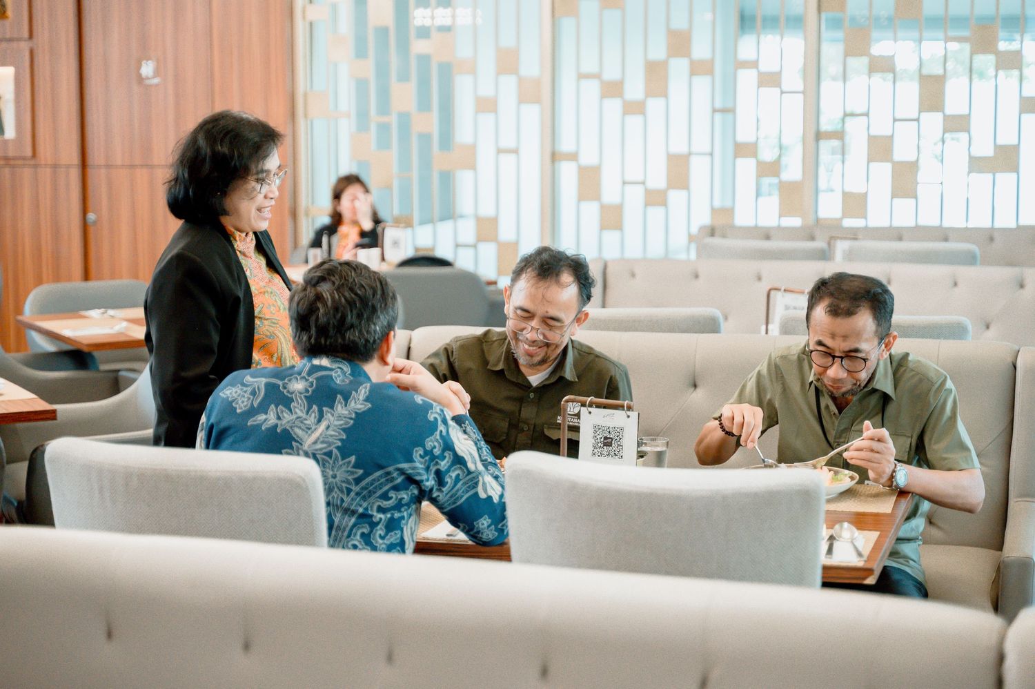 Group of professionals having a meeting in a modern lounge area with gray sofas and wooden decor.