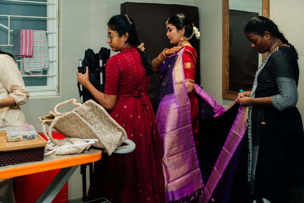Women in vibrant traditional Indian sarees and salwar kameez prepare together in a dressing room for a cultural celebration.
