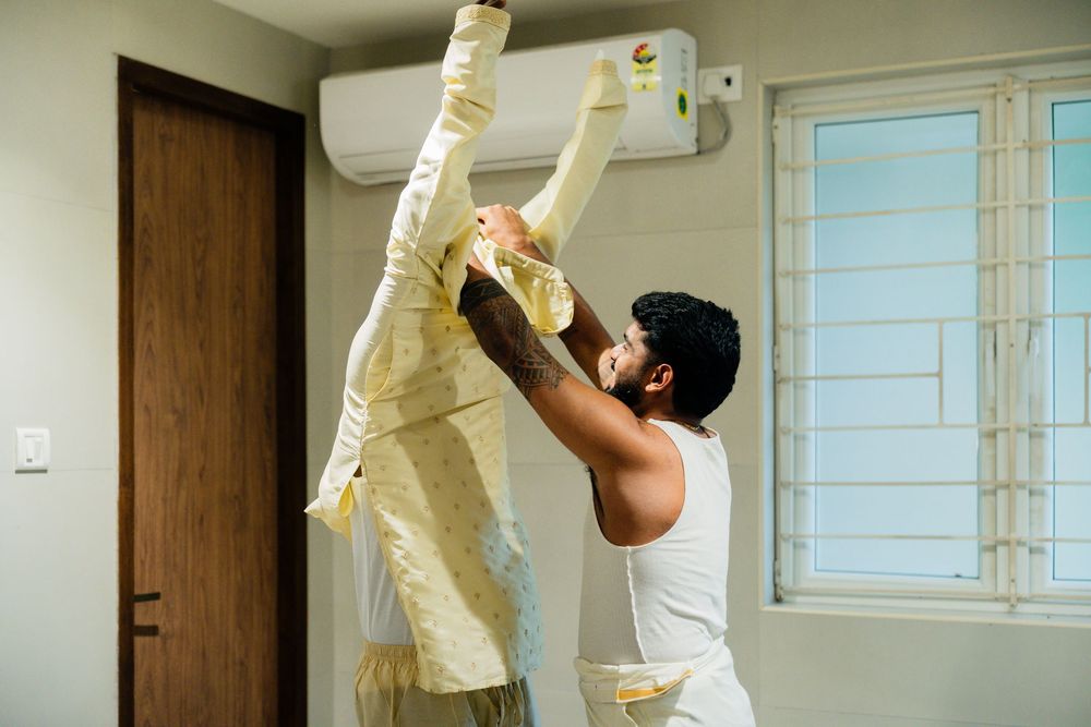 Man removing protective packaging from a wall-mounted air conditioner unit during installation in a modern room.