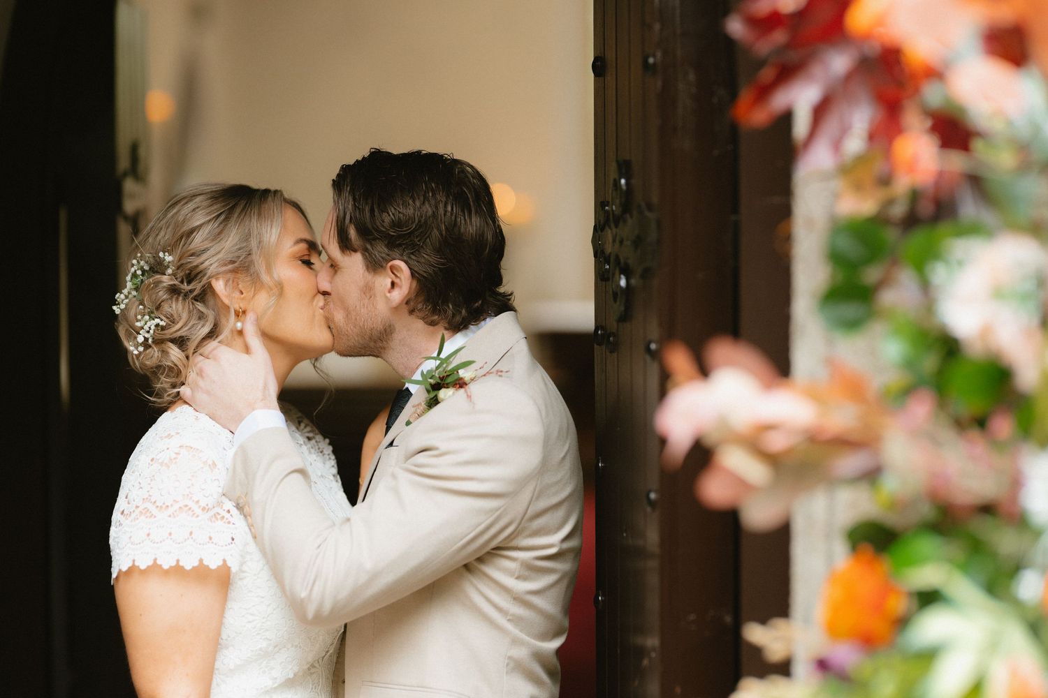 Bride and groom kissing beside flowers inside Macreddin Chapel at BrookLodge.