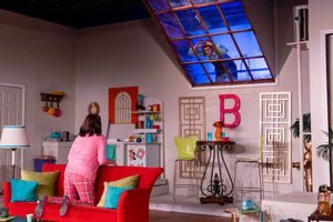 Colorful living room set with red sofa, skylight, and letter B decoration in a vibrant TV show studio.