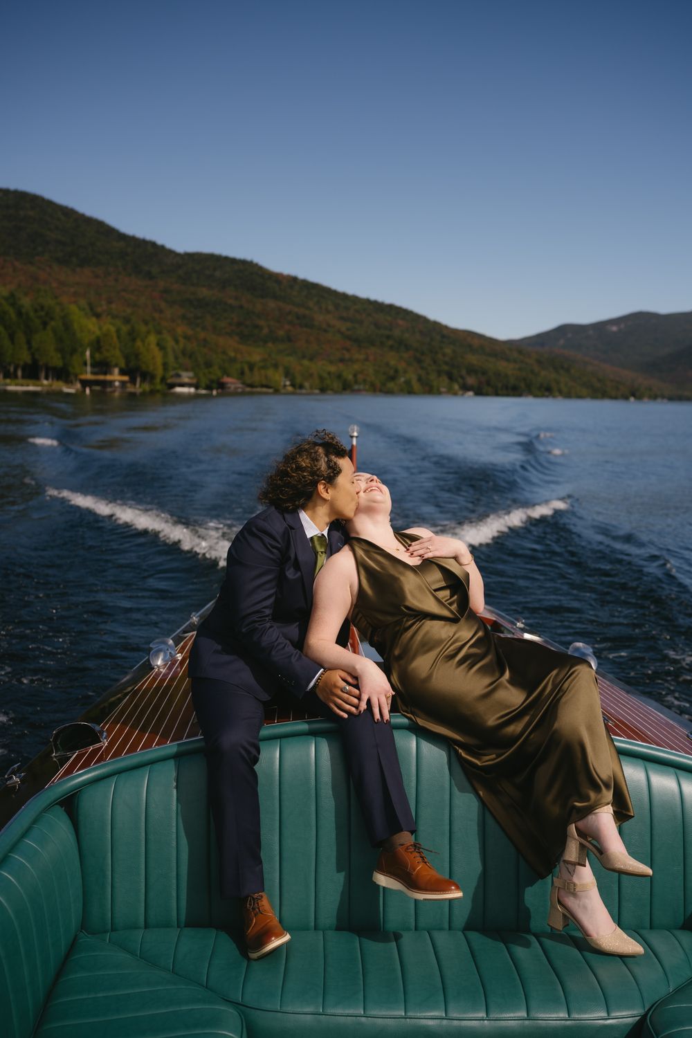 Couple sharing a romantic moment on a classic wooden speedboat on a mountain lake on a sunny day.