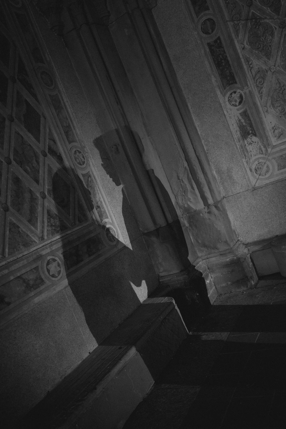 Black and white photo of a shadowy silhouette figure in an ornate historic building interior.