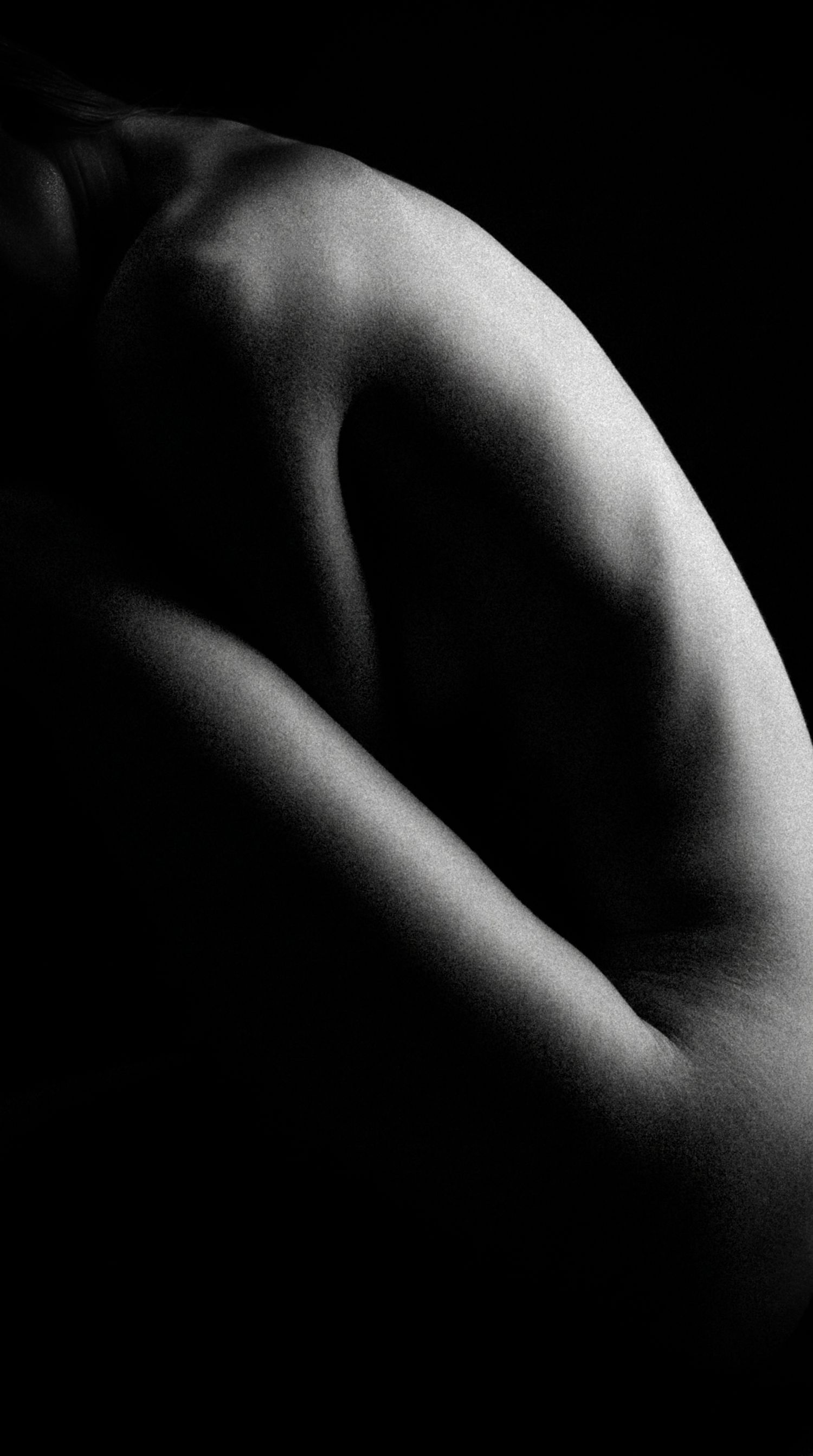 Black and white artistic nude close-up of human back and shoulder.