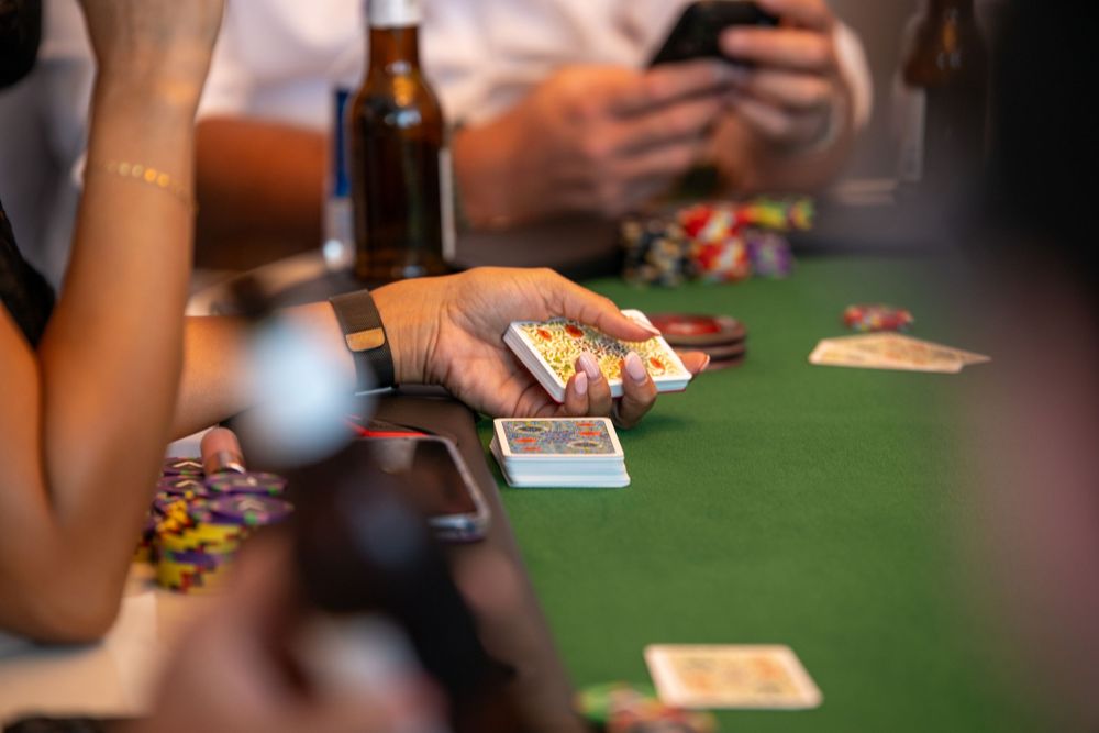 Players engage in a poker game at a green felt table with casino chips and playing cards.