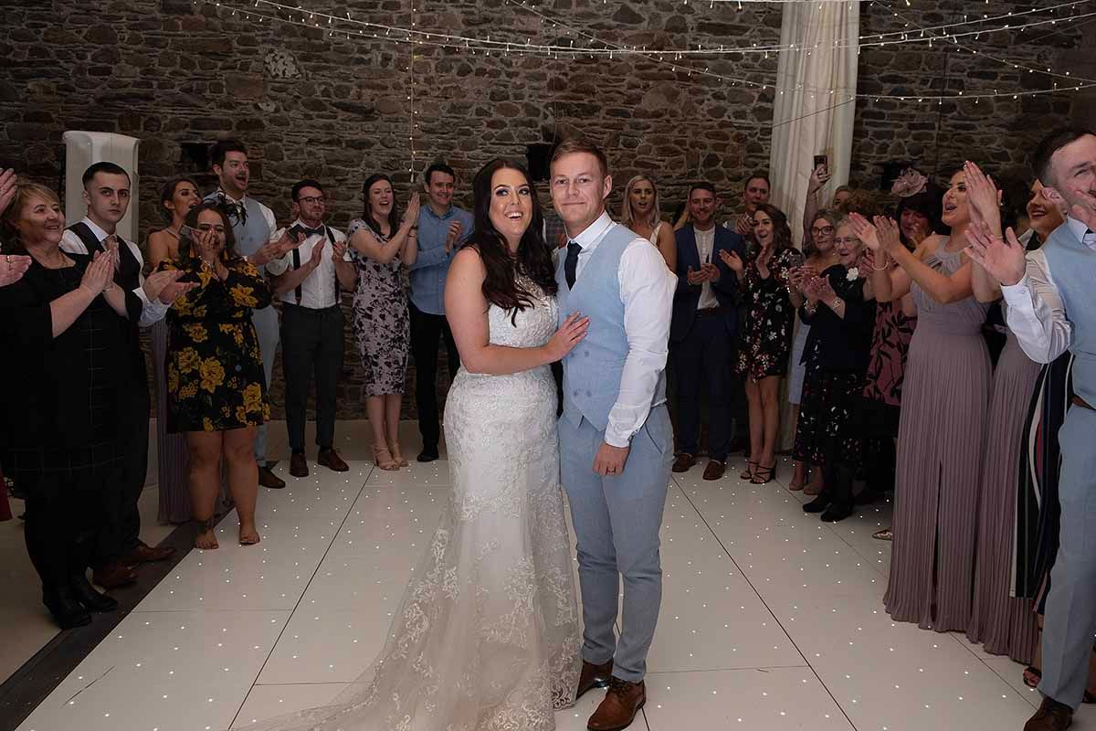 Bride and groom share first dance surrounded by clapping wedding guests at a unique wedding celebration at New House Farm Cockermouth
