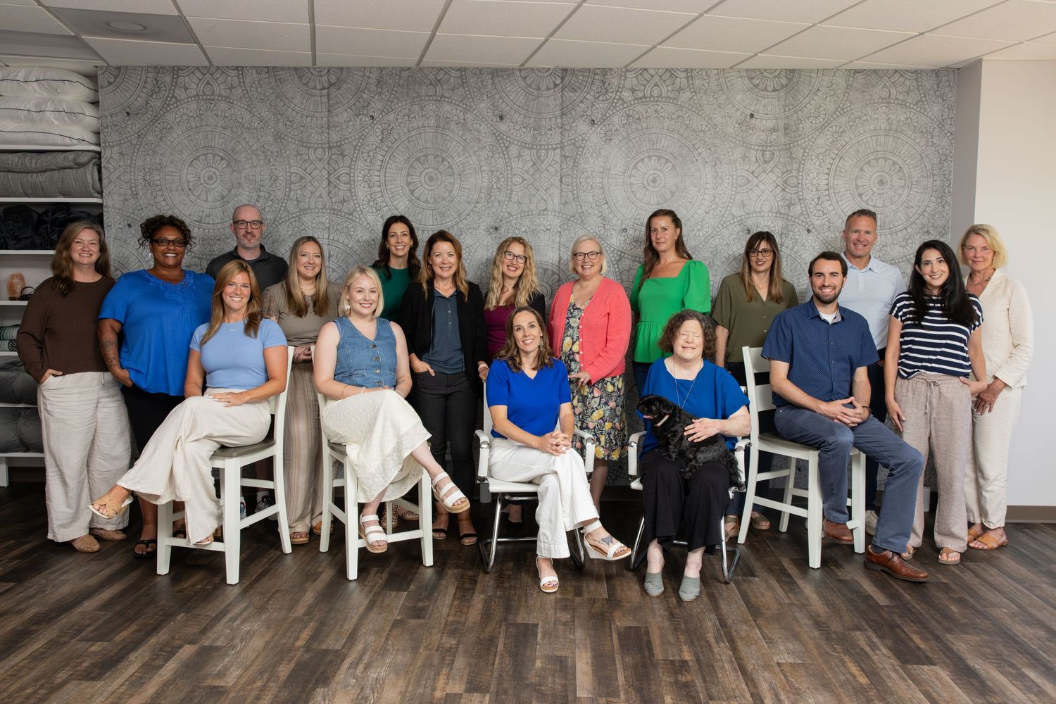 A diverse group of professionals posing together for a team photo in a modern office with concrete walls.