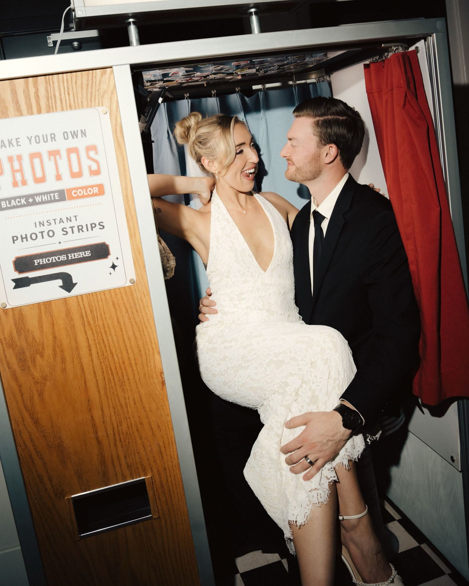 Vintage photo booth with red curtain and velvet rope barriers on a polished concrete floor at an event venue.
