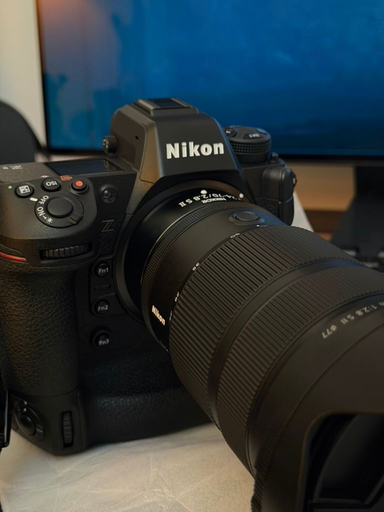 Nikon Z series mirrorless camera with attached zoom lens on desk near monitors.