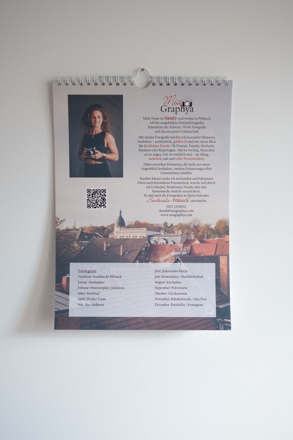 A spiral-bound photography calendar featuring a portrait of a female photographer and a cityscape image of a European town.