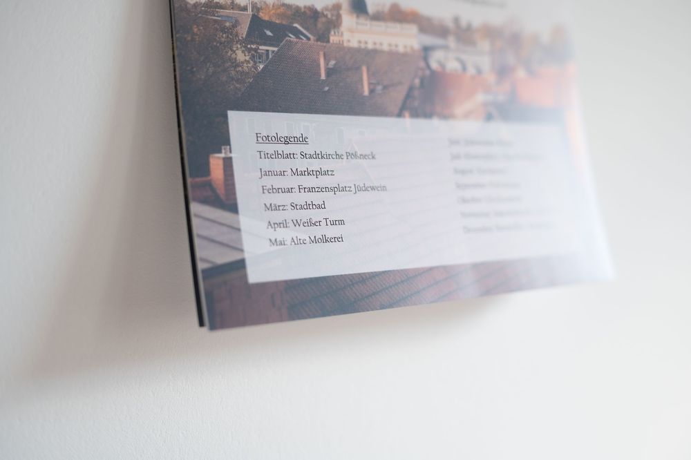 A close-up of a framed photo book or print leaning against a white wall, showing credits text over a cityscape image.
