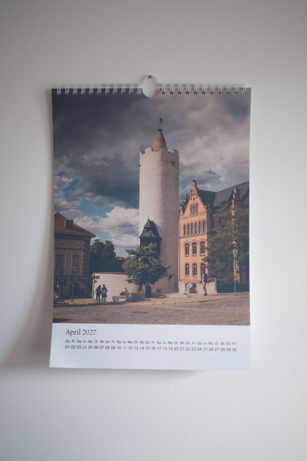 April 2027 wall calendar featuring a historic tower and ornate building under dramatic cloudy skies.